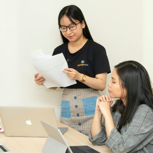 Two people reviewing documents whilst on their computer